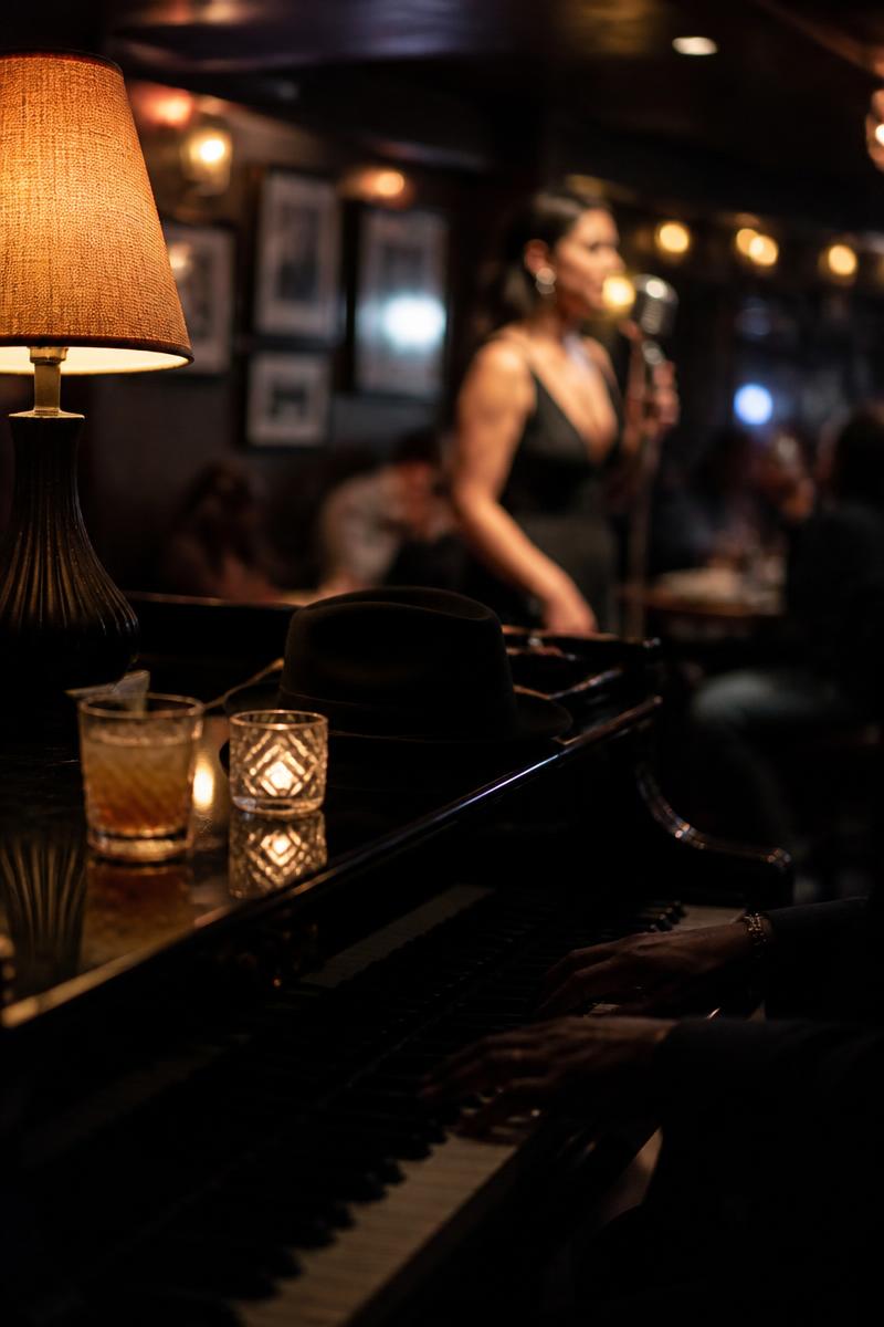 Dimly lit piano bar with a singer in the background and soft bokeh lights